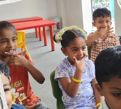 Children smiling with fingers on their chins during a class game